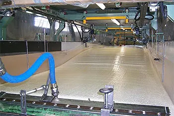 Vloeibaar schuimmengsel dat op een bewegende transportband rijst tot een doorlopend schuimblok